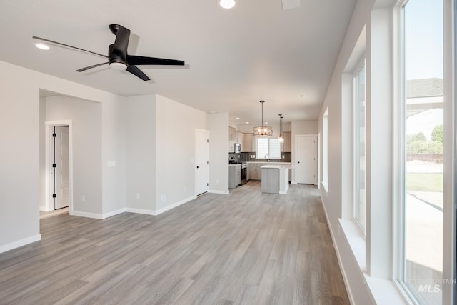 unfurnished living room featuring sink, light wood-type flooring, and ceiling fan