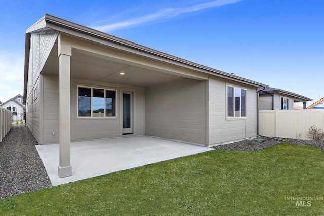 rear view of house featuring a patio, a yard, and fence