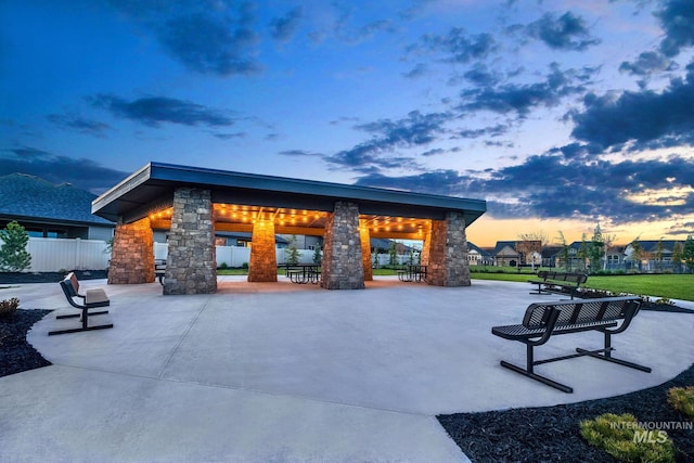 pool at dusk featuring a gazebo, a patio area, and fence