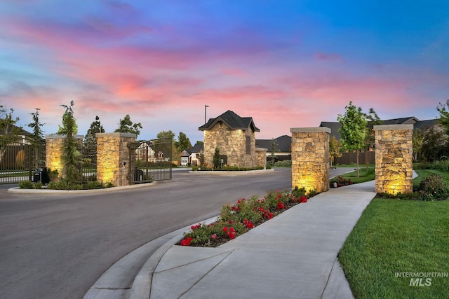 view of road featuring curbs, a gated entry, sidewalks, and a gate