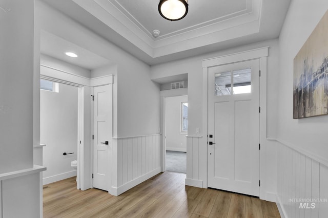 entrance foyer featuring wainscoting, light wood-type flooring, and a tray ceiling