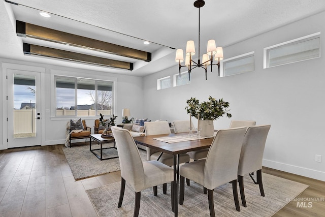 dining area featuring beamed ceiling, a notable chandelier, wood finished floors, recessed lighting, and baseboards