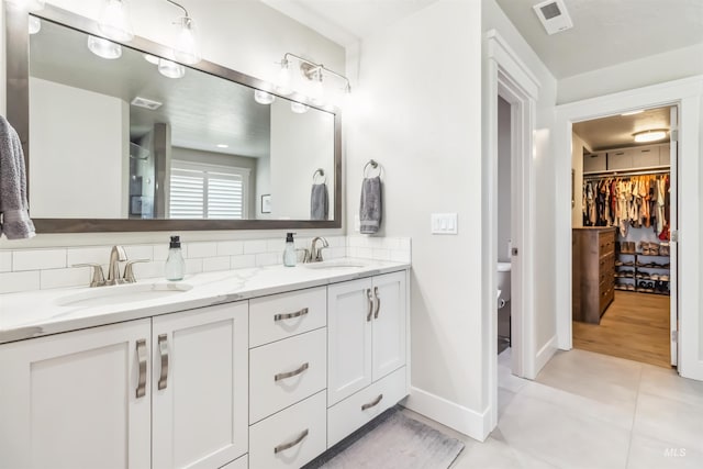 9115 S Palena Ave, Kuna, ID 83634 - full bath with double vanity, decorative backsplash, baseboards, toilet, and a walk in closet