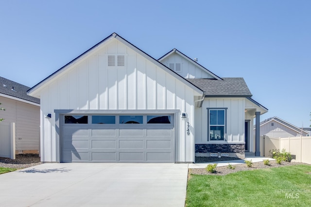 modern inspired farmhouse with a shingled roof, concrete driveway, an attached garage, board and batten siding, and fence