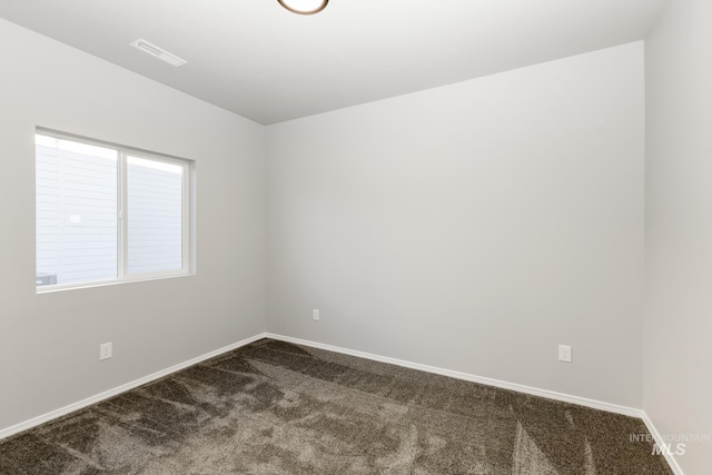 unfurnished room with dark carpet, visible vents, and baseboards