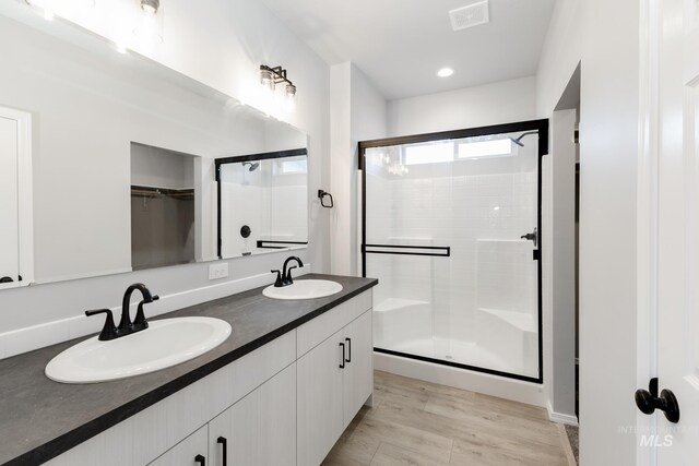 full bathroom featuring double vanity, a stall shower, visible vents, and a sink