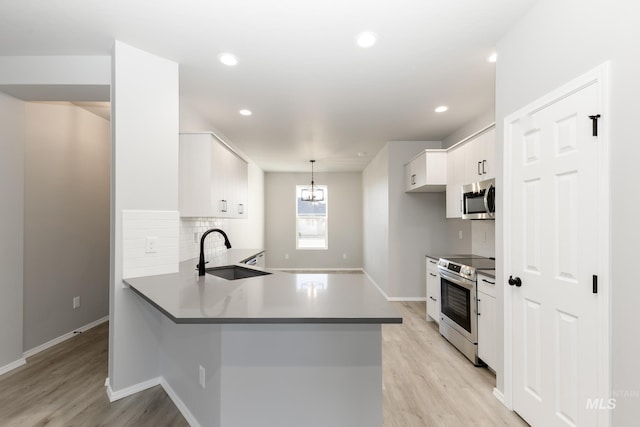 kitchen with light wood-style flooring, stainless steel appliances, a sink, white cabinetry, and backsplash