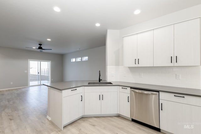 kitchen featuring light wood finished floors, open floor plan, a sink, dishwasher, and a peninsula