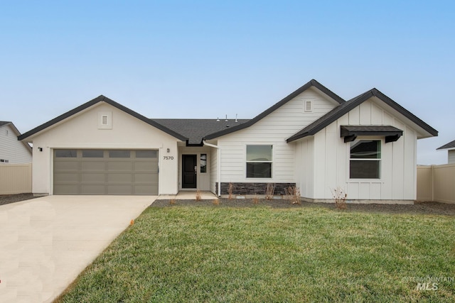 view of front of home with an attached garage, fence, concrete driveway, a front lawn, and board and batten siding