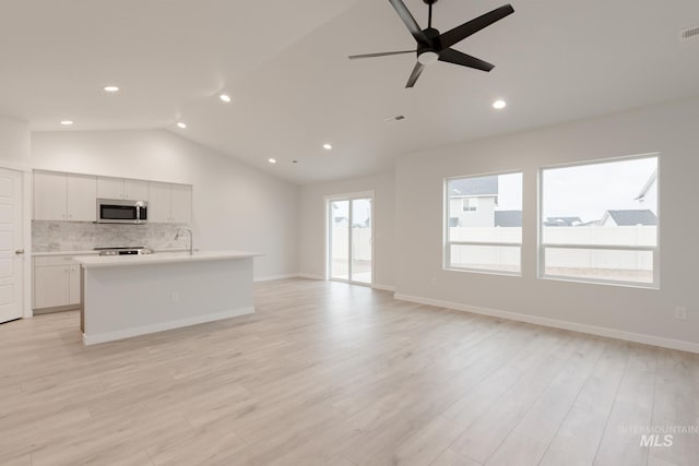 unfurnished living room featuring lofted ceiling, light wood-type flooring, visible vents, recessed lighting, and a ceiling fan