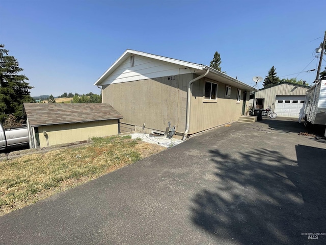 view of home's exterior with an outdoor structure, a garage, and aphalt driveway