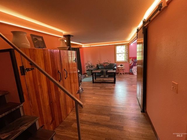 hall with stairs, a barn door, and wood finished floors