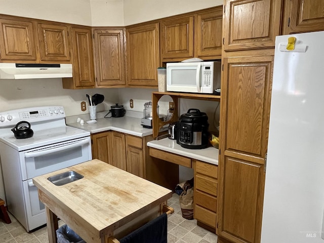 kitchen with under cabinet range hood, white appliances, built in study area, and light countertops