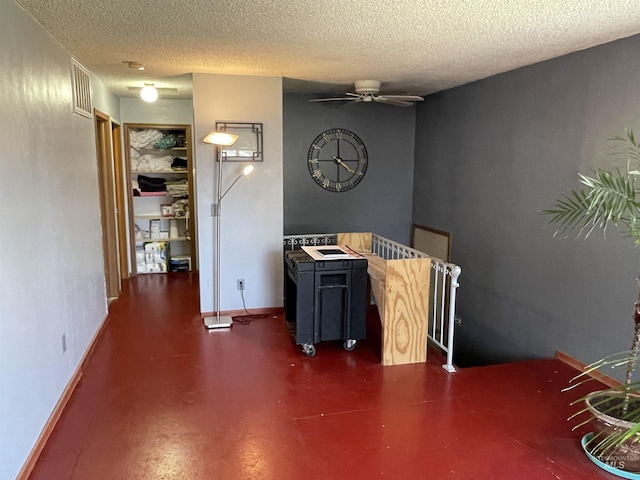 interior space featuring a ceiling fan, baseboards, concrete floors, and a textured ceiling