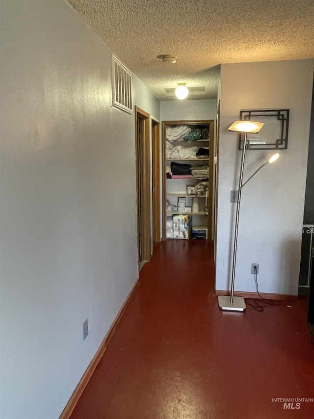 hall featuring visible vents, baseboards, and a textured ceiling