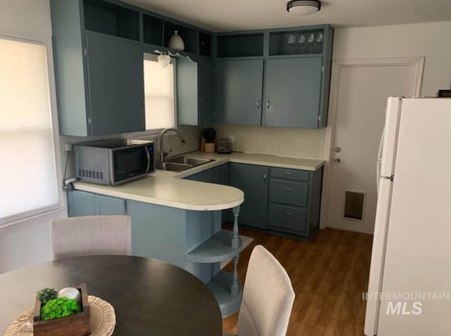 kitchen with kitchen peninsula, dark hardwood / wood-style flooring, white refrigerator, and sink