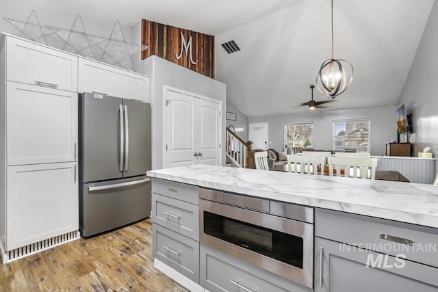 1003 Lauren Ln, Filer, ID 83328 - kitchen featuring gray cabinets, hanging light fixtures, vaulted ceiling, light wood-style floors, and appliances with stainless steel finishes