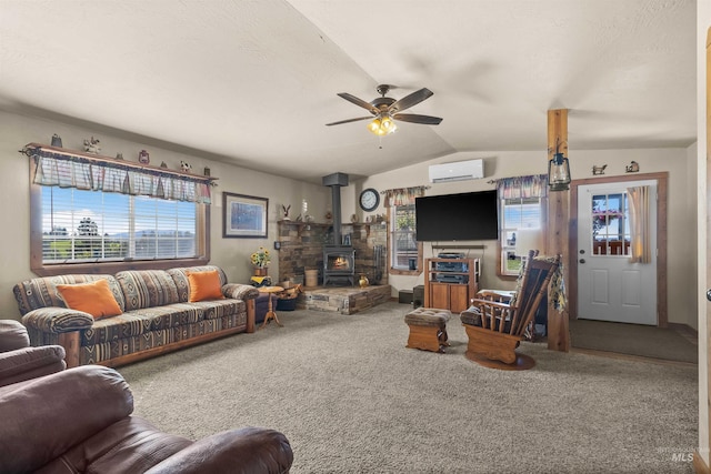 carpeted living room featuring a wood stove, a ceiling fan, a wall mounted AC, and vaulted ceiling