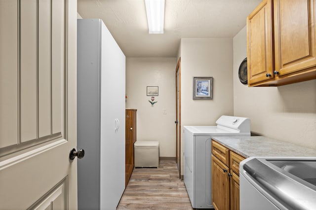 laundry room featuring cabinet space, light wood finished floors, and independent washer and dryer