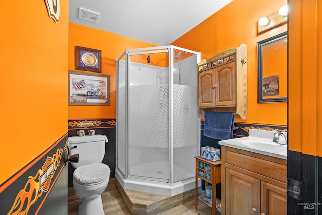full bath featuring toilet, visible vents, wainscoting, and wood finished floors