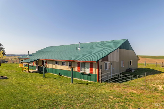 rear view of house with a lawn, fence, and metal roof
