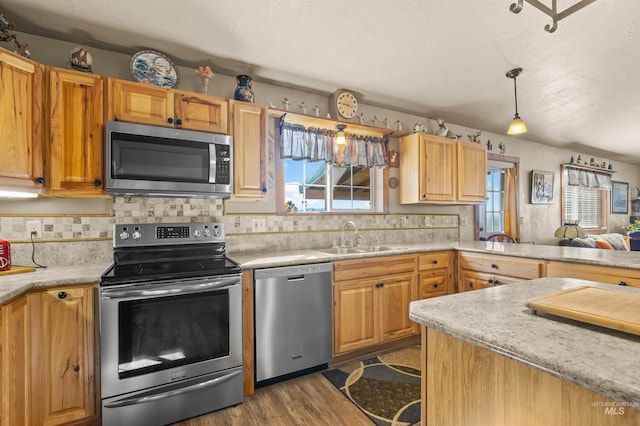 kitchen with decorative backsplash, dark wood-style flooring, a sink, light countertops, and stainless steel appliances