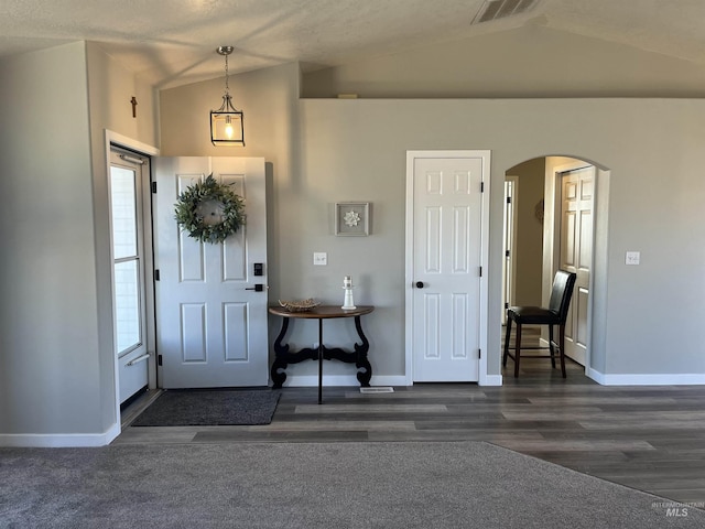 entrance foyer featuring arched walkways, lofted ceiling, visible vents, and baseboards