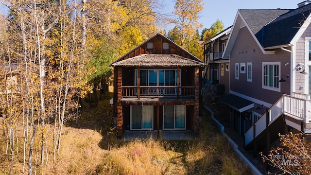 back of property with central air condition unit and a balcony