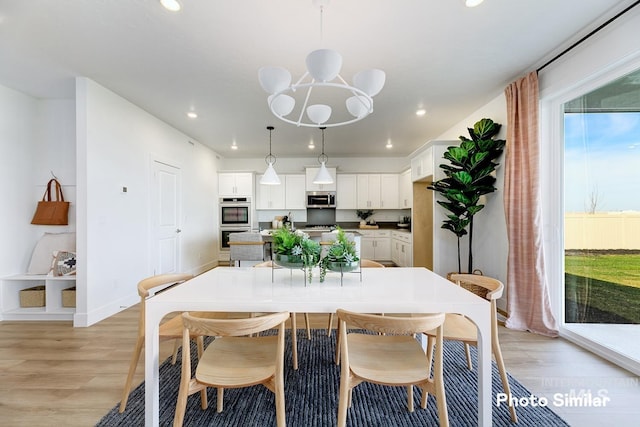 dining space with light hardwood / wood-style floors and a chandelier