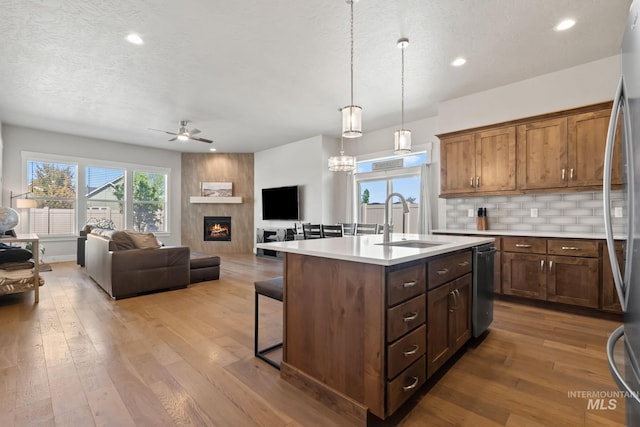 kitchen with a sink, ceiling fan, light countertops, a fireplace, and a breakfast bar area