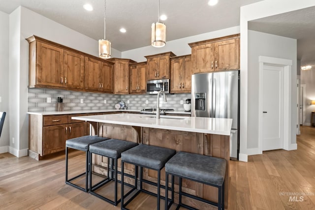 kitchen with stainless steel appliances, light countertops, light wood-type flooring, decorative backsplash, and recessed lighting