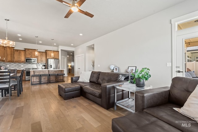 living area featuring a ceiling fan, light wood-type flooring, a chandelier, and recessed lighting