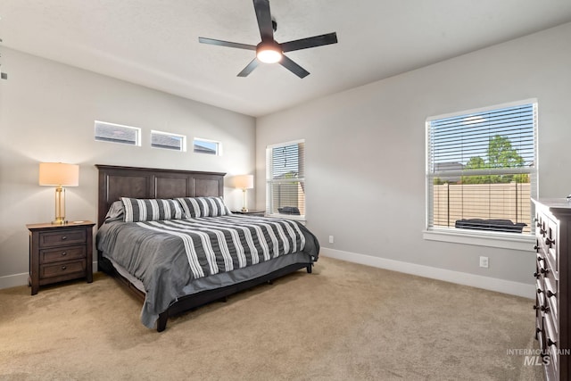 bedroom with light colored carpet, baseboards, and a ceiling fan