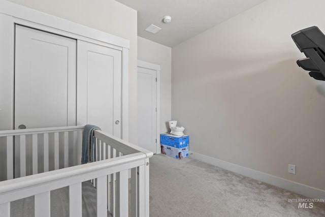 unfurnished bedroom featuring carpet, a closet, baseboards, and a crib