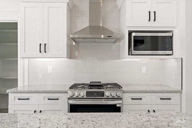 kitchen featuring wall chimney exhaust hood, decorative backsplash, white cabinetry, and appliances with stainless steel finishes