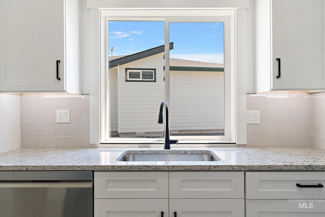 kitchen with white cabinetry, dishwasher, light stone counters, and sink