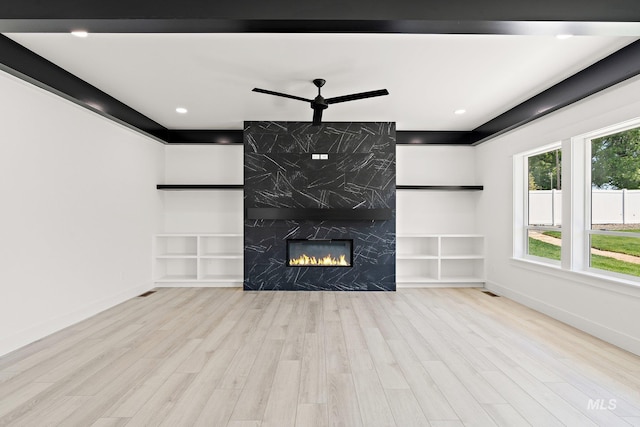 unfurnished living room with ceiling fan, light hardwood / wood-style floors, and a high end fireplace