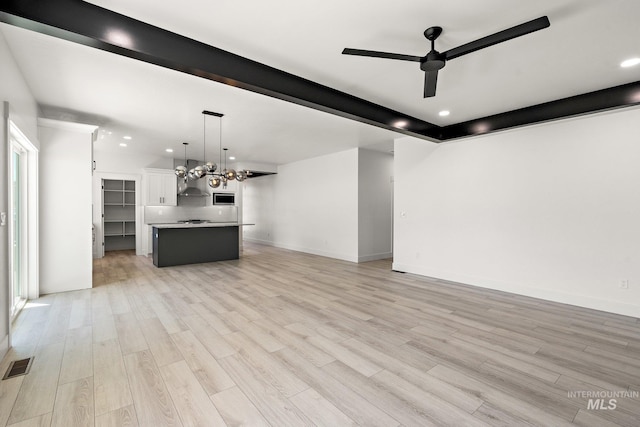 unfurnished living room featuring ceiling fan with notable chandelier and light hardwood / wood-style floors