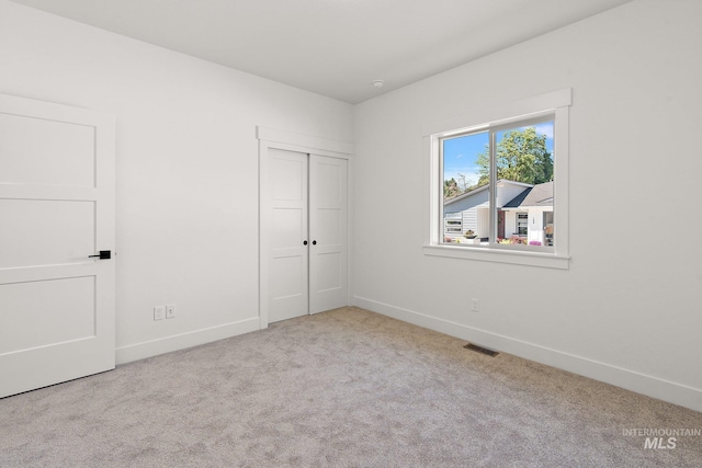 unfurnished bedroom with light carpet and a closet