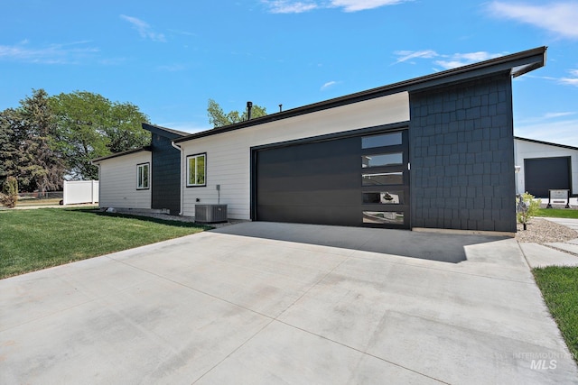 view of front of house featuring a garage, a front yard, and central AC