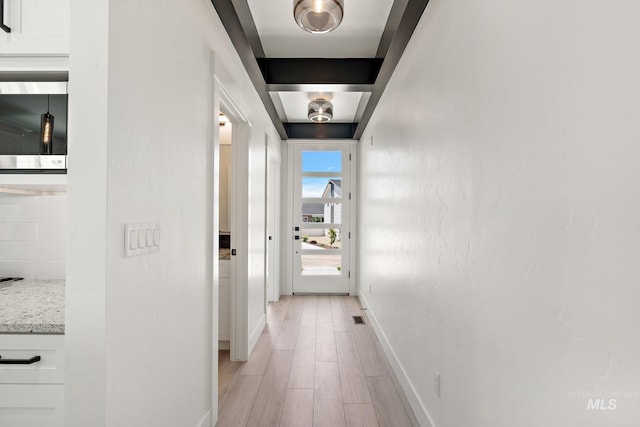 hall with beamed ceiling and light hardwood / wood-style flooring