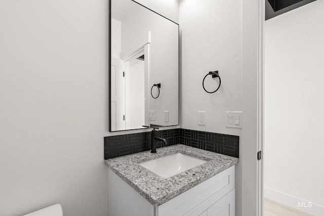 bathroom with decorative backsplash, vanity, and hardwood / wood-style flooring