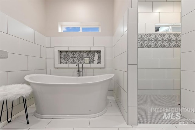 bathroom featuring shower with separate bathtub and tile walls