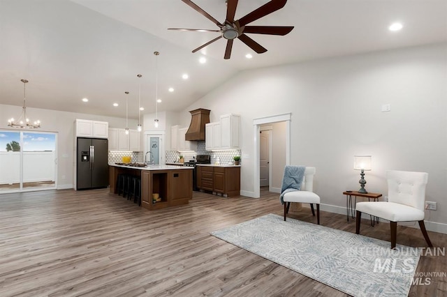 kitchen featuring dark brown cabinetry, hanging light fixtures, a center island with sink, stainless steel appliances, and light hardwood / wood-style floors