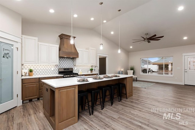 kitchen featuring stainless steel range, a large island, a kitchen breakfast bar, and custom exhaust hood