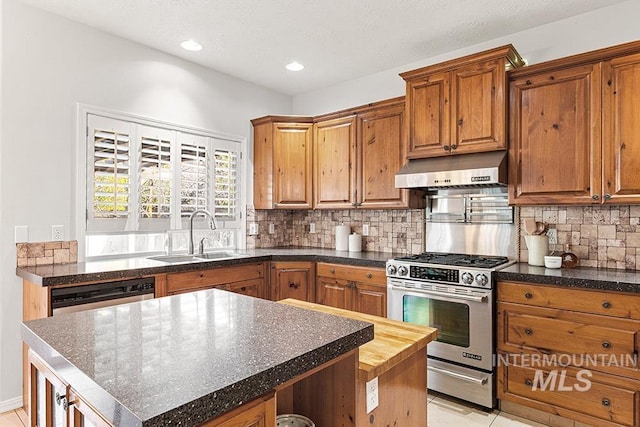 kitchen with tasteful backsplash, brown cabinetry, stainless steel gas range, under cabinet range hood, and a sink