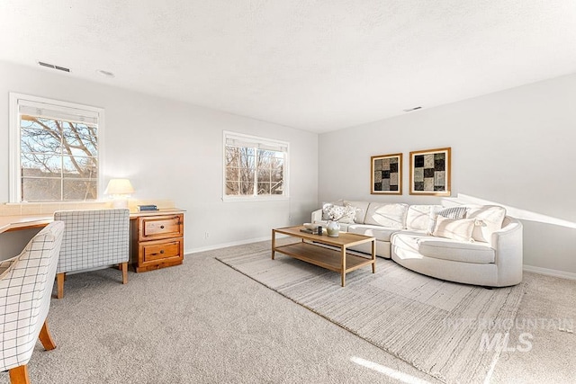 living area with baseboards, carpet flooring, visible vents, and a healthy amount of sunlight