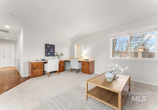 office featuring a wealth of natural light, light colored carpet, visible vents, and baseboards