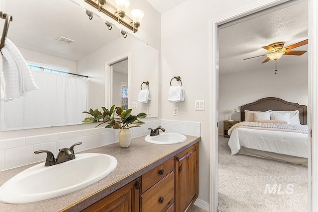 ensuite bathroom with ensuite bathroom, double vanity, a sink, and visible vents