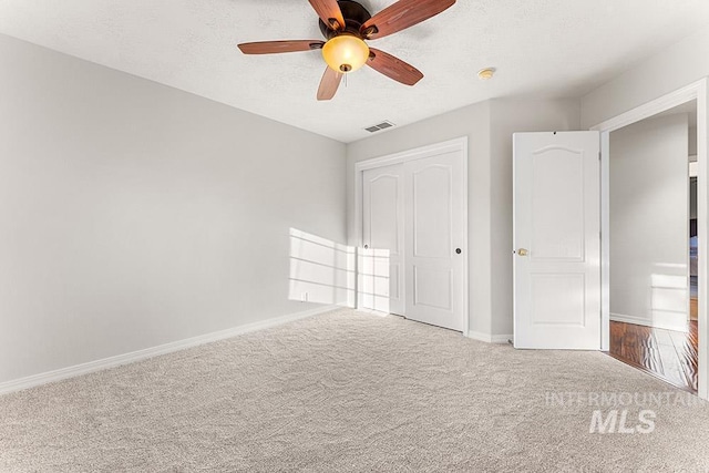 unfurnished bedroom with a textured ceiling, carpet flooring, visible vents, and baseboards